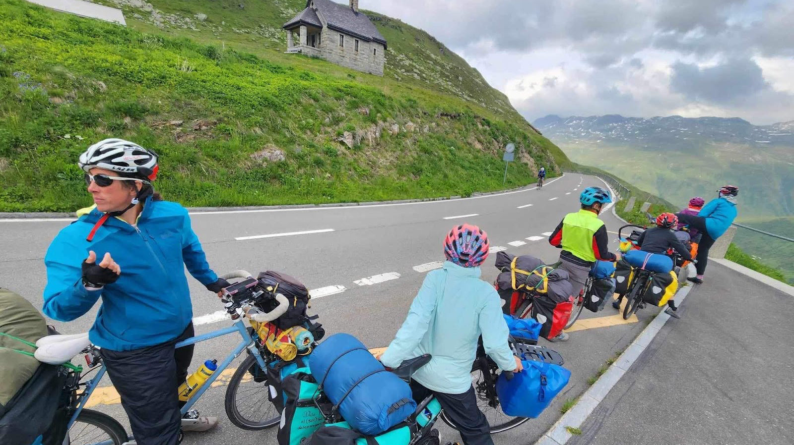 Family loaded up to bikepack Europe passing through a mountain and taking a break on the roadside with packs and gear from Grand Trunk and more