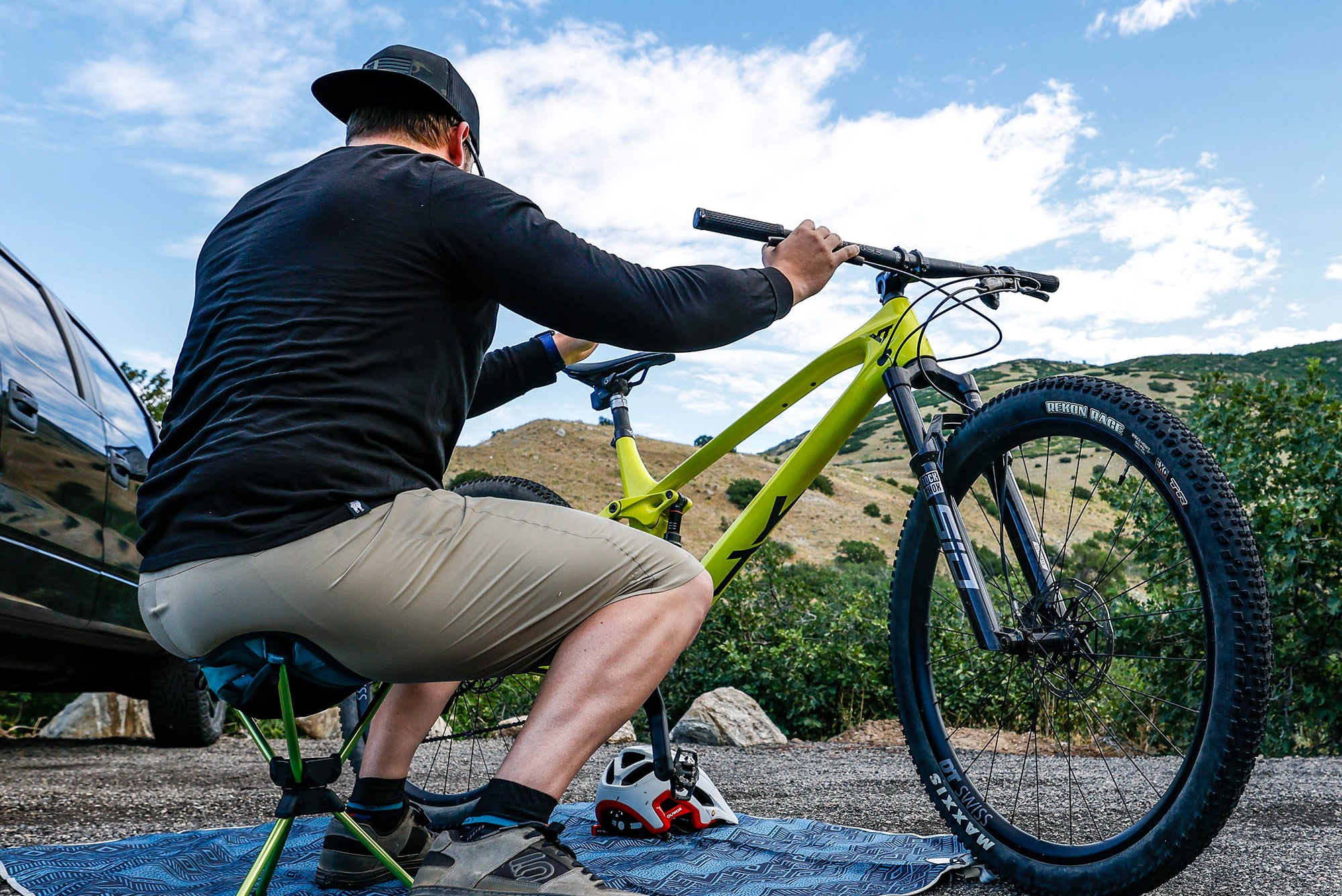 man sits on compass 360° stool to work on mountain bike before hitting the trail