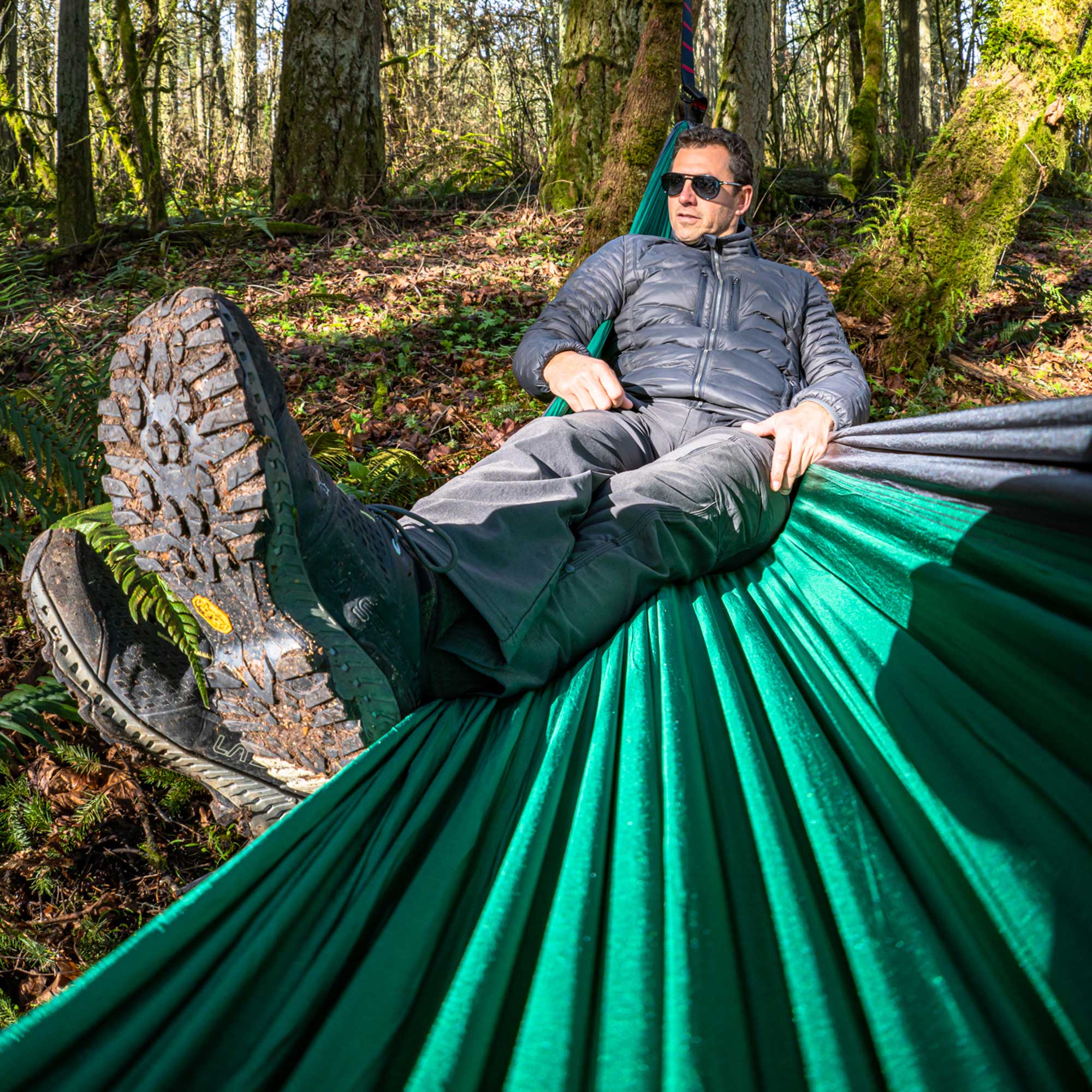 Man relaxing in a green hammock in a forest setting