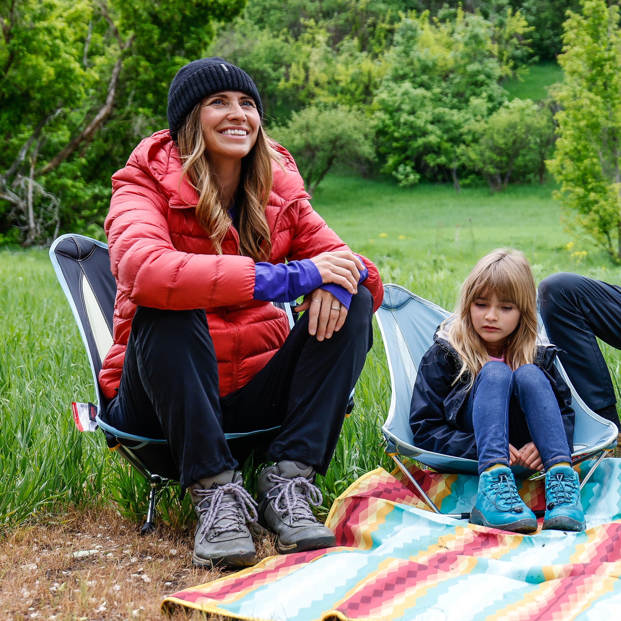woman sits in the mantis chair girl sits in mayfly chair on meadow mat in meadow forest