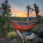 skeeter beeter hammock set up in the woods with a beautiful sunset happening in the background