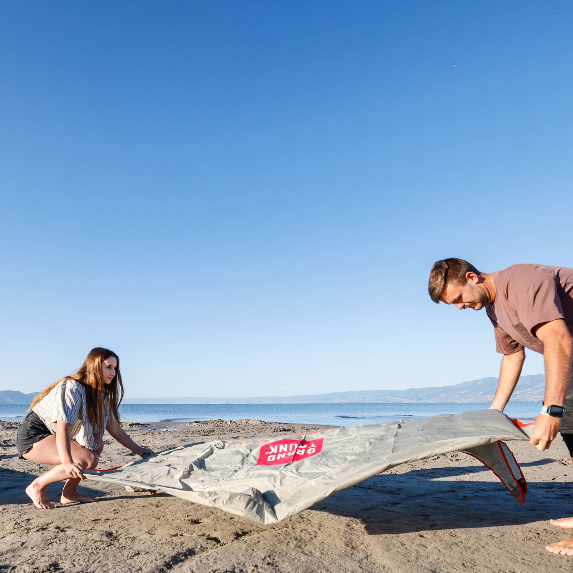 man and woman setting up the shadecaster 2 on the beach