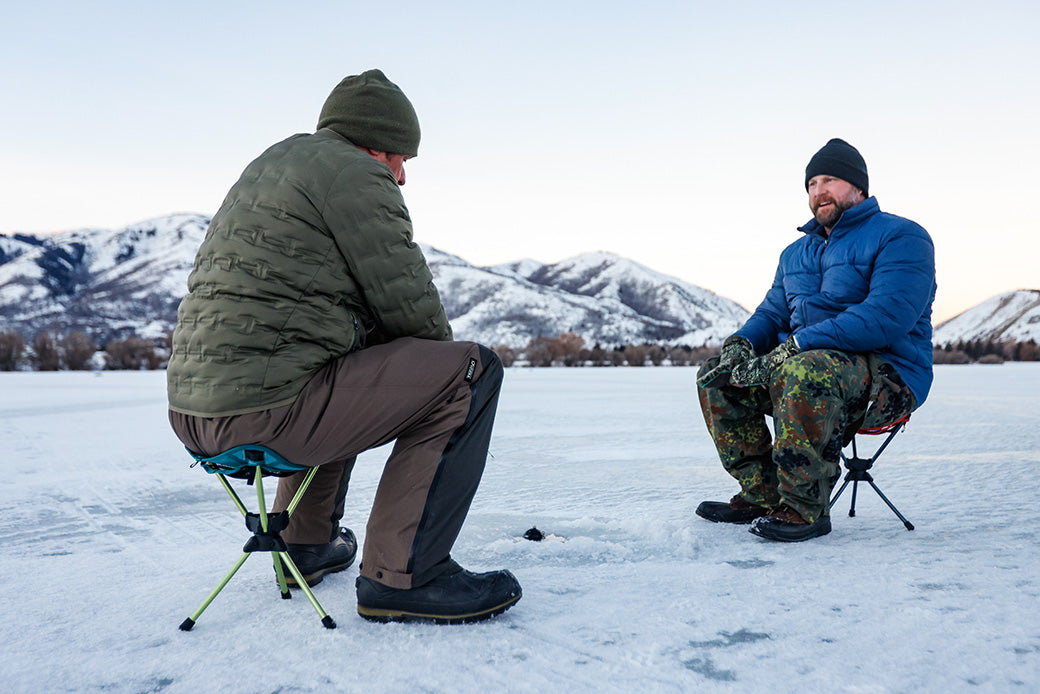Two men ice fishing with the compass 360 stool with a beautiful mountainscape background