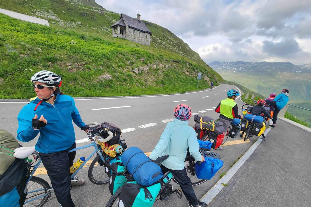 Family loaded up to bikepack Europe passing through a mountain and taking a break on the roadside with packs and gear from Grand Trunk and more