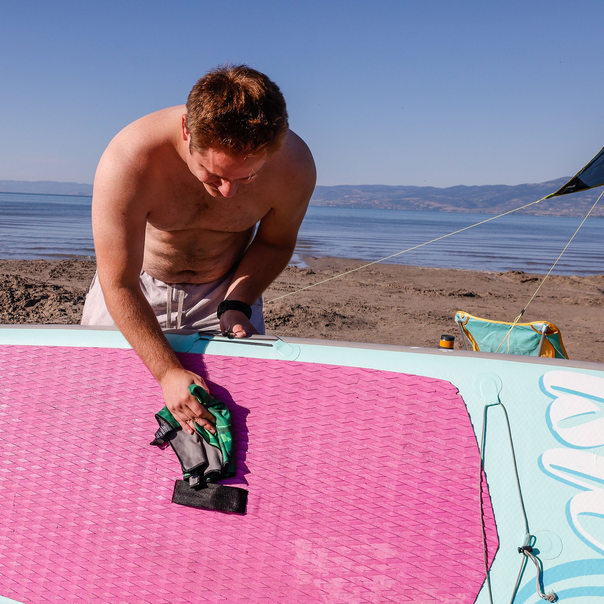 man uses microfiber towel to clean SUP paddle board