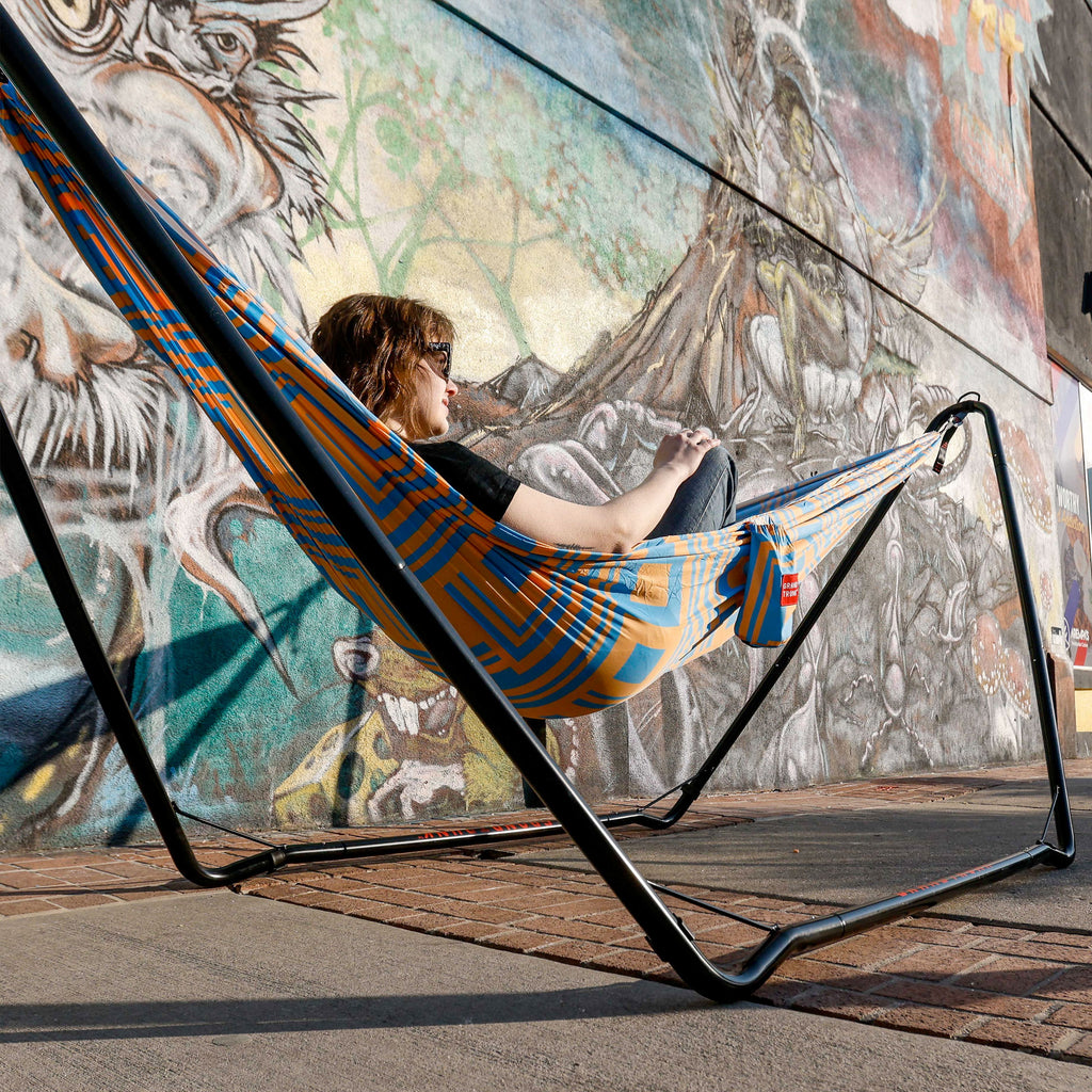 Woman in hammock suspended by hammock stand urban mural sunshine