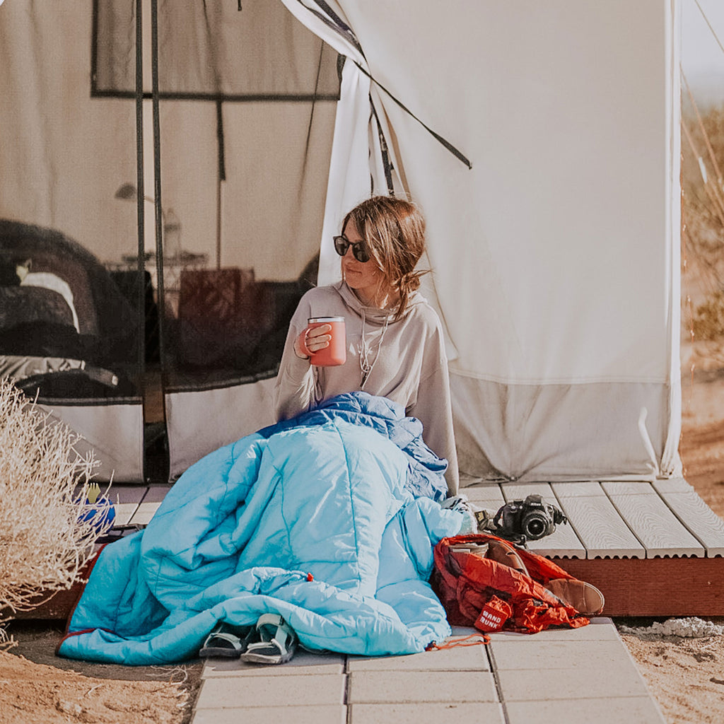 woman sipping coffee in the thermaquilt on a desert morning in a glamping experience