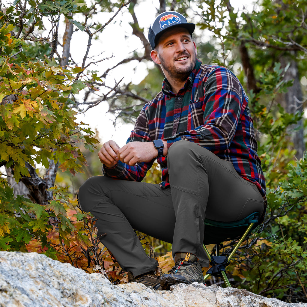 man sits on compass 360 stool  smiling with fall foliage