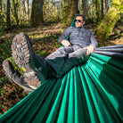 Man relaxing in a green hammock in a forest setting