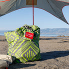 eco tote bag on a lakeside beach underneath the ShadeCaster with lots of gear inside