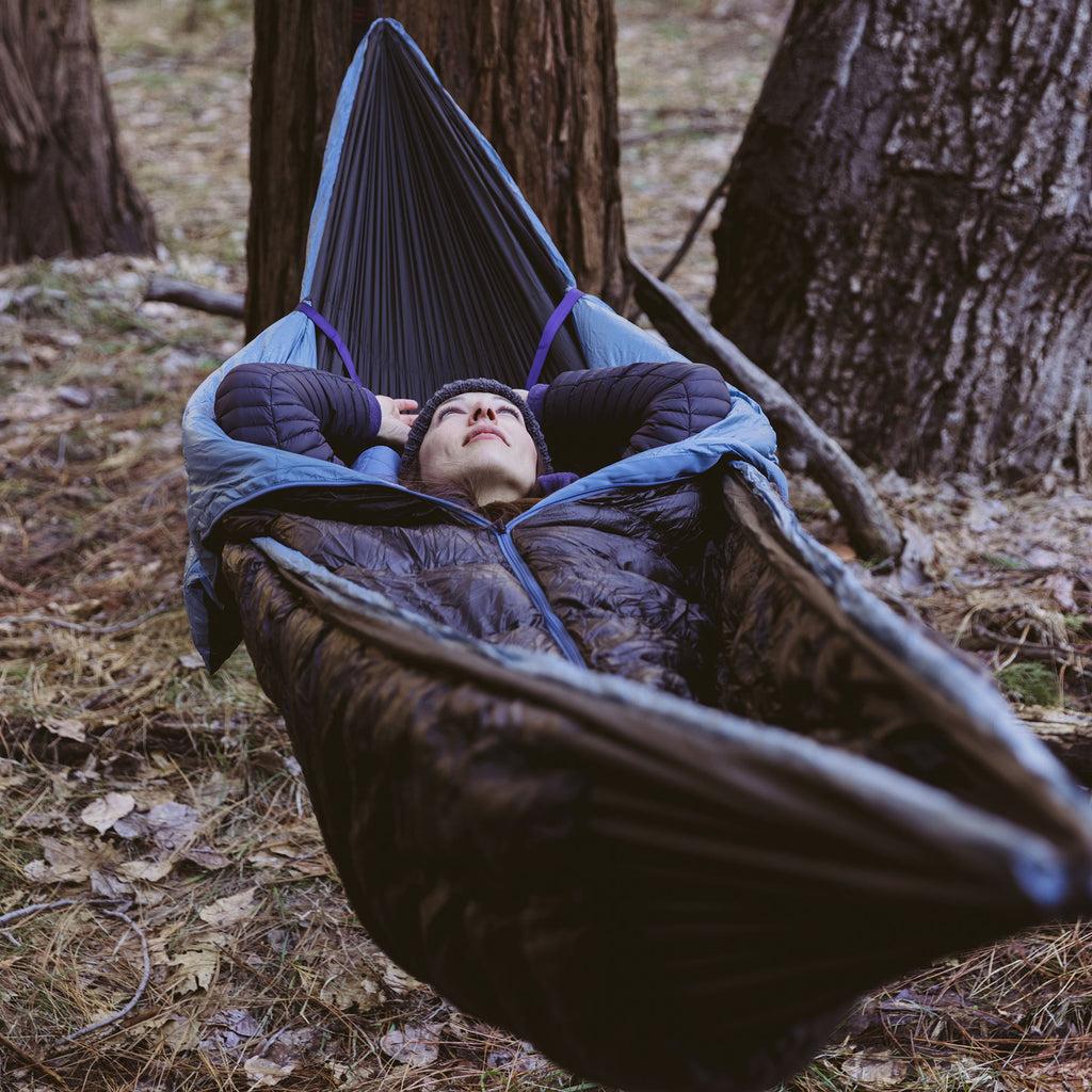 Woman walking up from a good nights sleep in the Evolution sleeping bag Hammock by Grand Trunk with siesta pillow in forest outdoor adventure