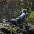 Man enjoying the view of a waterfall in Grand Trunk Mafly chair balanced on uneven terrain and rocky ground