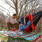 Couple and dog with meadow mat underneath the rovr chair and compass 360 stool