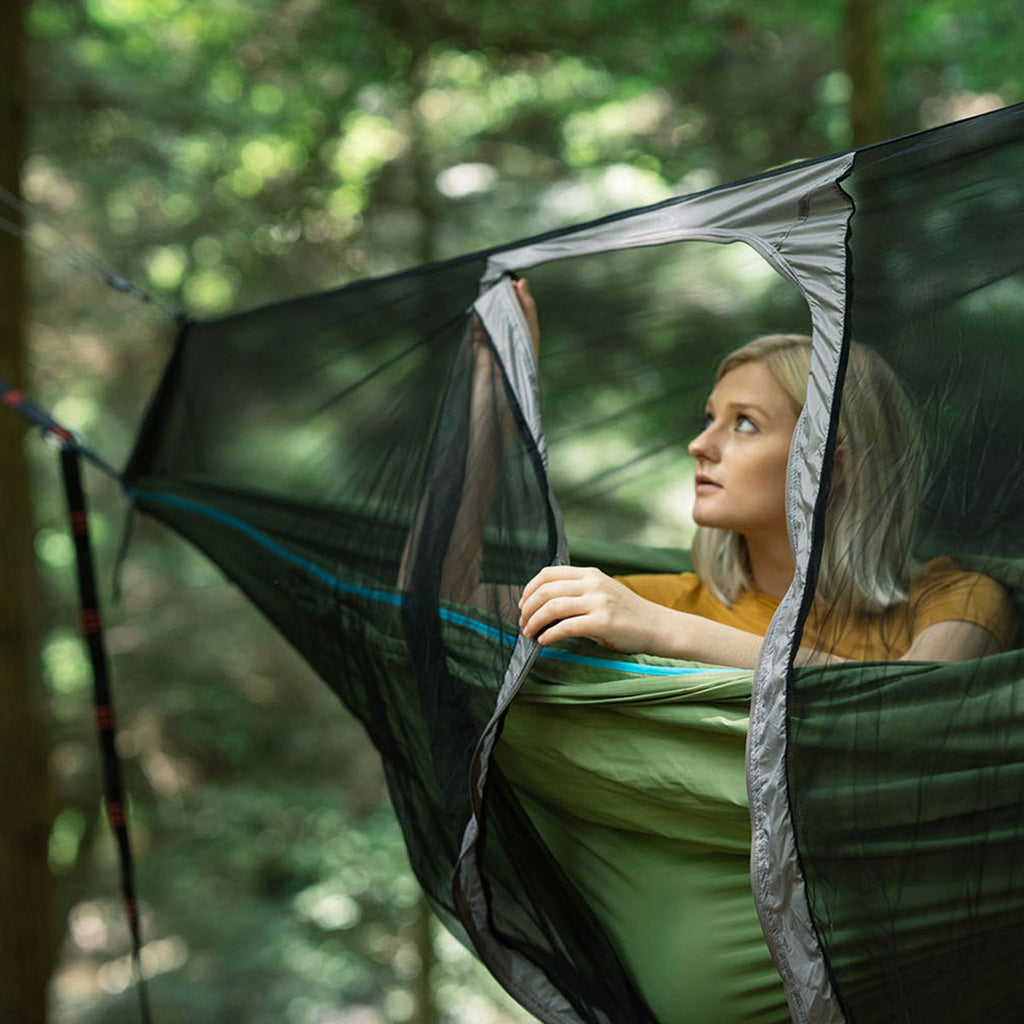 Mozzy bug net with woman inside hammock while opening up j-zipper