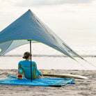 woman with surfboard sitting on the mayfly chair on a parasheet underneath the shadecaster 2 on cocoa beach in florida