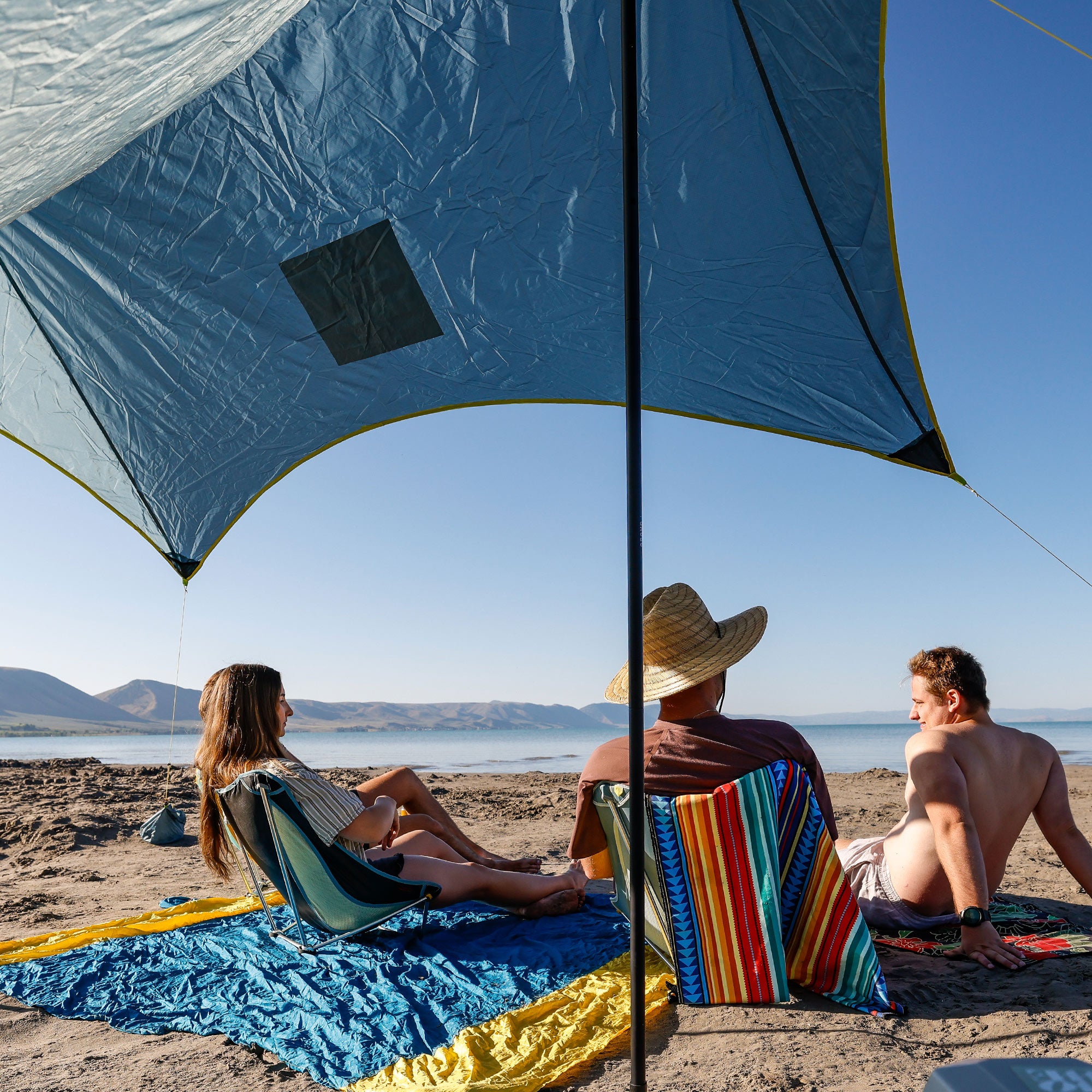 group hanging out under the shadecaster 4 with a parasheet, mayfly chairs, and microfiber towels